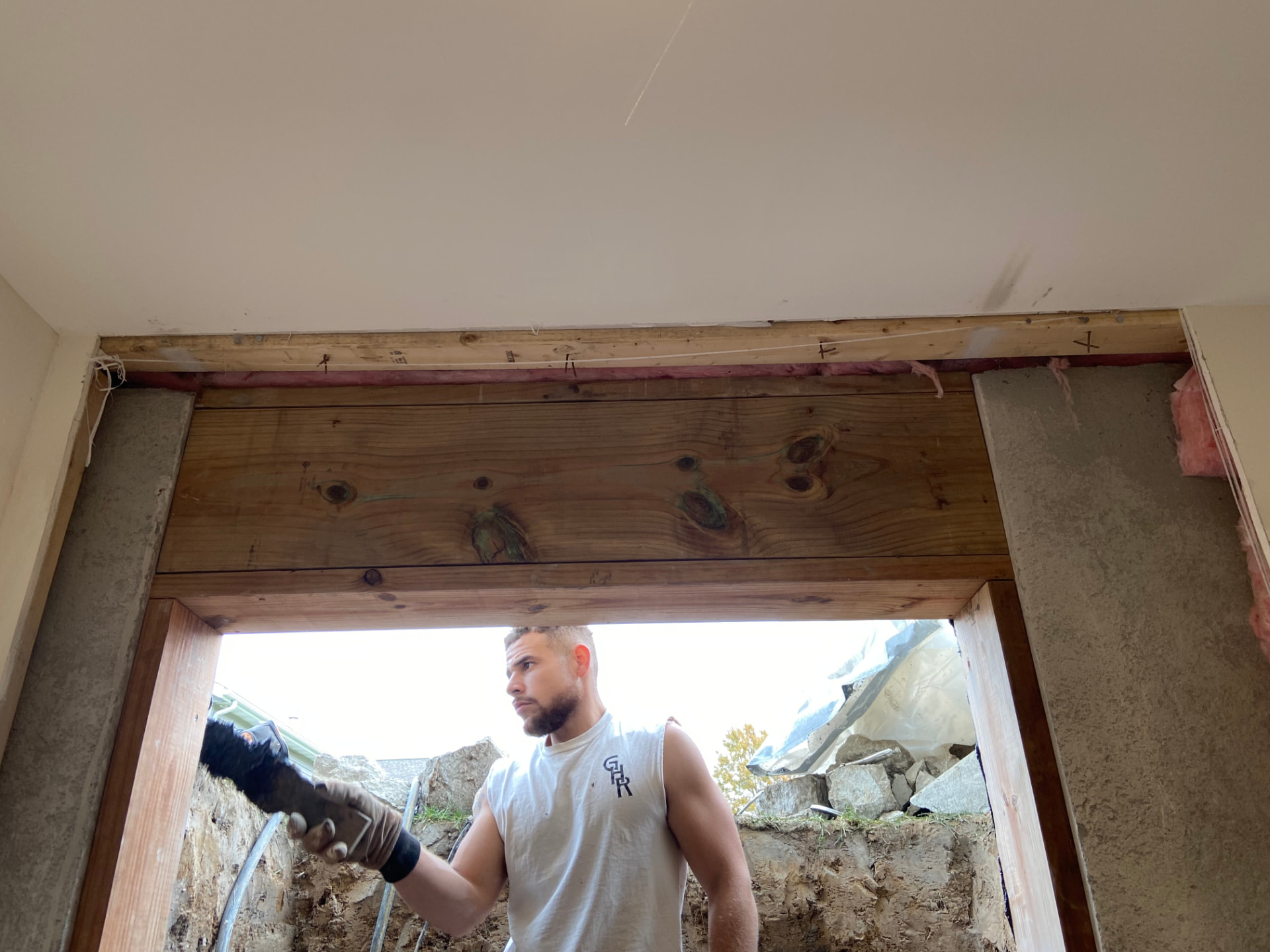 GHR crew member working under a newly framed wood header above a basement egress opening.