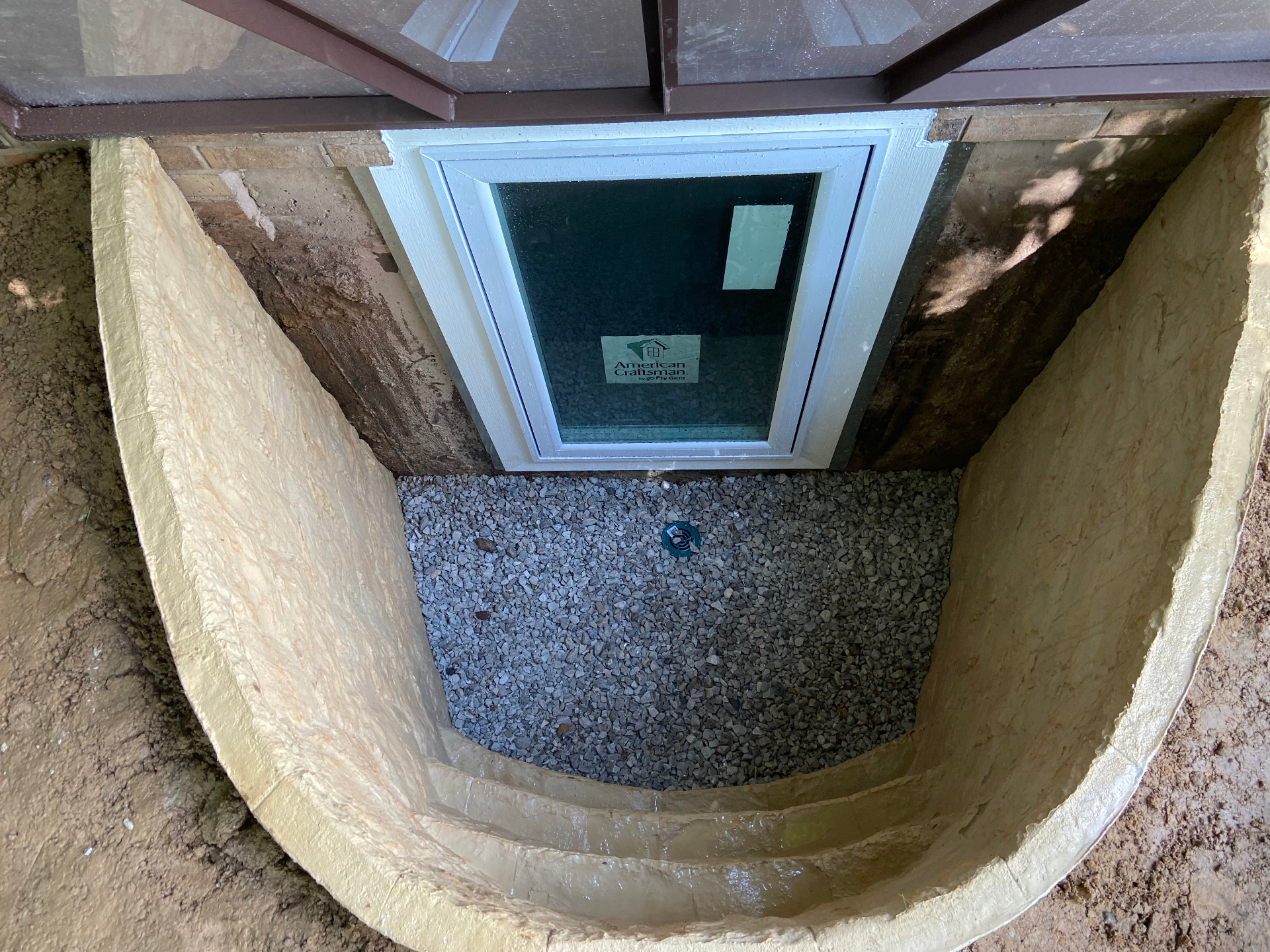 Egress window installation with a tan Rockstep fiberglass well and a casement window, by GHR Egress Windows.