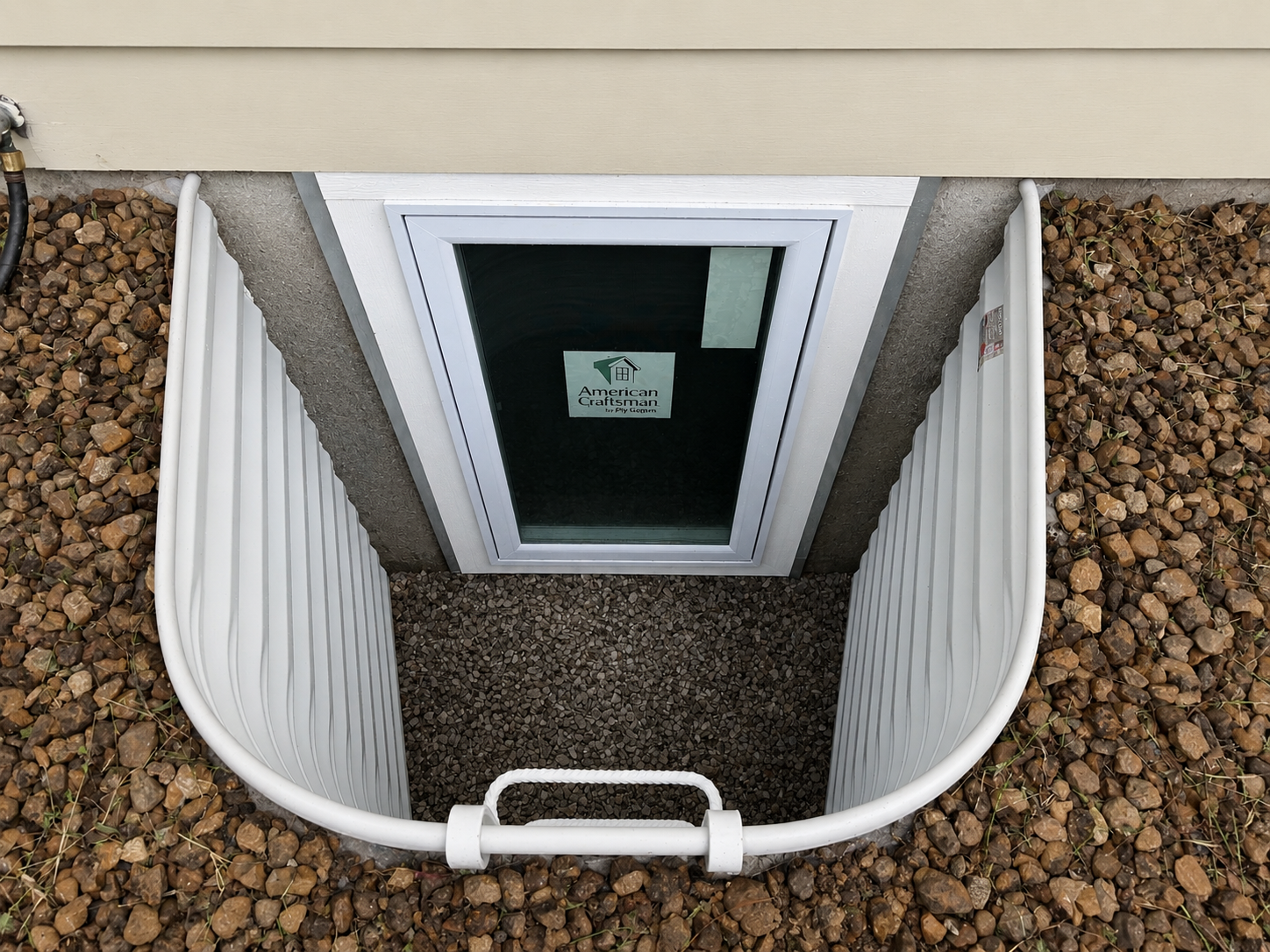 Finished egress window installation with a standard white steel window well and a casement window, code-compliant install by GHR Egress Windows.